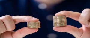 Man Holding Two Coin Stacks To Compare