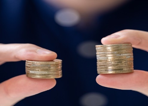 Man Holding Two Coin Stacks To Compare