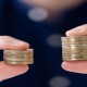 Man Holding Two Coin Stacks To Compare